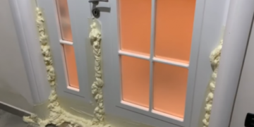 Qytetari mbyll derën me shkumë që të mos i futet uji në shtëpi