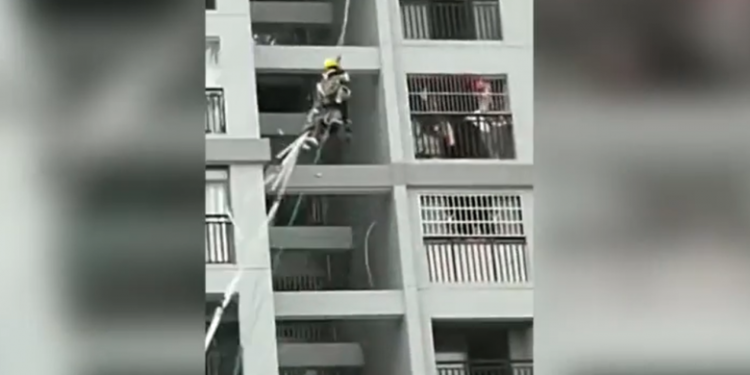 Të lidhur për litarë, dy punëtorët në Kinë lëkunden nga erërat e forta